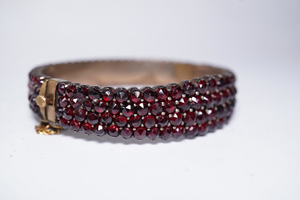 A suite of garnet and paste jewellery, comprising: a brooch, 5cm diameter; a bangle, inner circumference 16cm; two rings, sizes I and M; a pair of earrings, and a single earring, each set with rose-cut garnets; and a pai